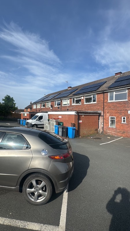A row of terraced houses with solar panels across several adjoining roofs